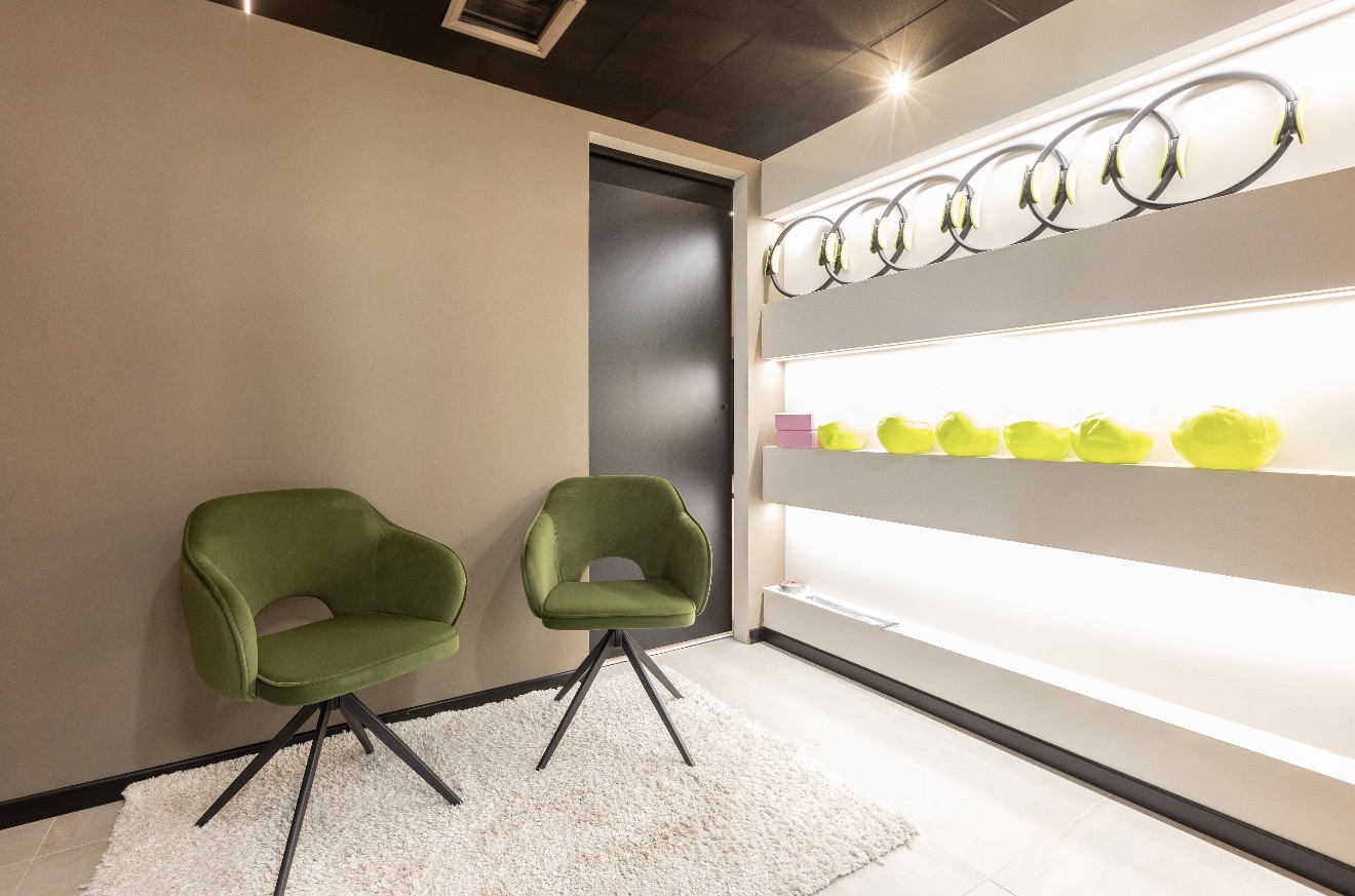 Poltroncine verdi e piccoli attrezzi nell’accoglienza del Pilates Studio